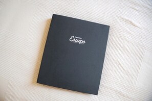 A black book with the title 'TINY AWAY Escape' on a textured white surface.
