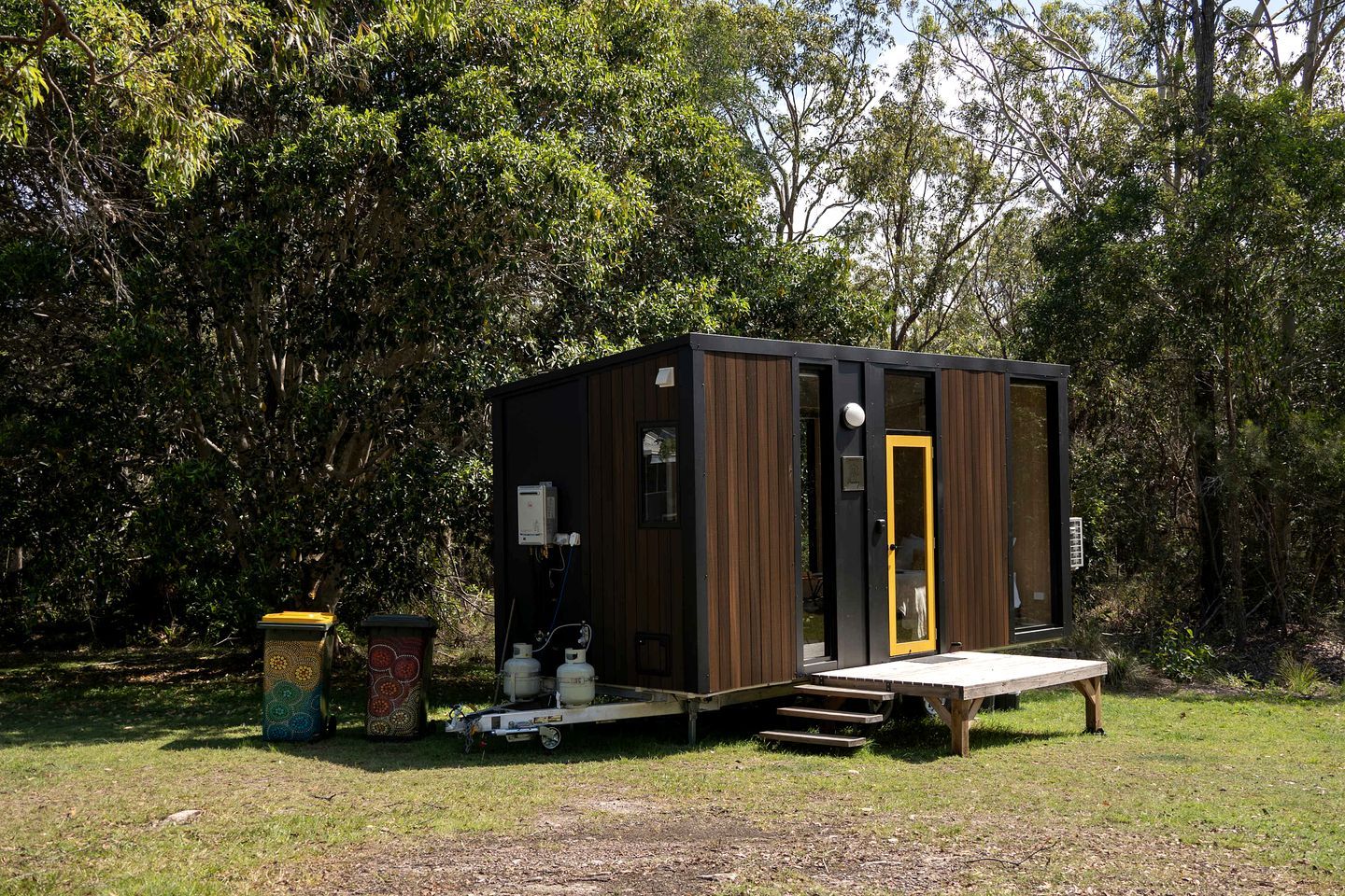 Una cabaña pequeña de una sola habitación, con puerta, ventana y un banco afuera.