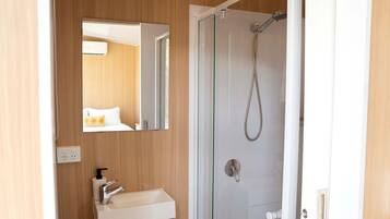 Une salle de bain avec une douche, un lavabo et un miroir.