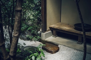 Un jardín japonés tradicional con un banco de madera, un sendero de piedra y abundante vegetación.