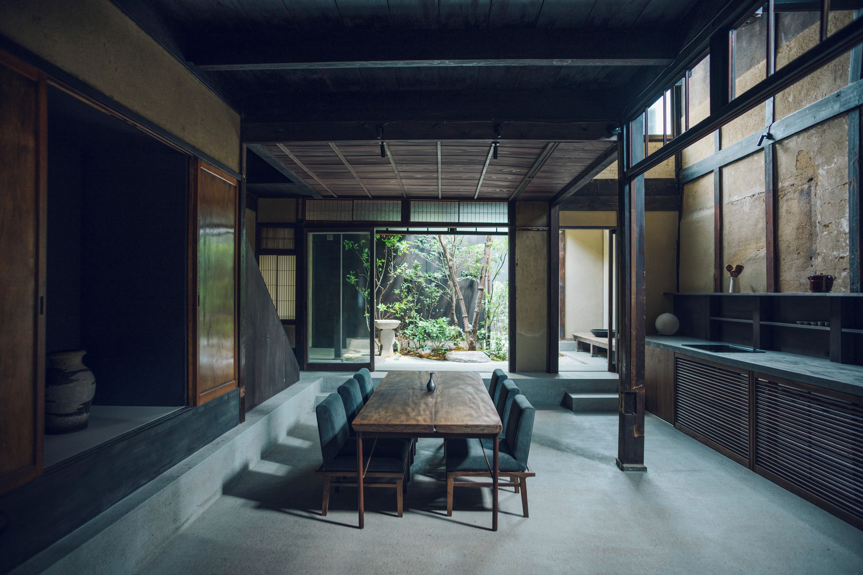 Ein traditionelles japanisches Interieur mit Tatami-Boden, einem niedrigen Holztisch und Blick auf einen Garten.
