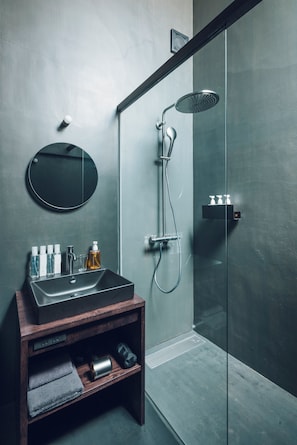 A modern bathroom with a glass-enclosed shower, a round mirror, and a wooden vanity with a sink. - MOTOMOU (Kyoto)