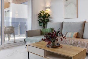 A modern living room with a sofa, a coffee table, and a potted plant. - Apartment Valonia Punta Prima BR3 (Torrevieja)