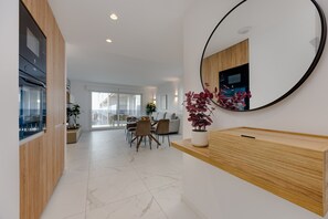 Eine moderne Küche mit integrierten Geräten, ein Essbereich mit einem Glastisch und ein großer Spiegel an der Wand.