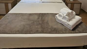 A neatly made bed with a headboard, two bedside tables with lamps, and a large ceiling light.