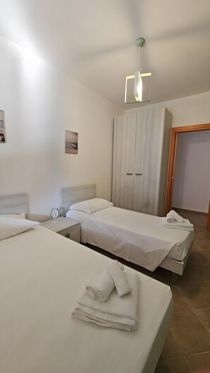 Een hotelkamer met twee bedden, een kledingkast, een nachtkastje en een hanglamp.