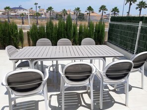A rooftop patio with a rectangular table and six chairs. - Groundfloor Varudi Aguas Nuevas (Torrevieja)