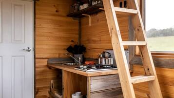 Een kleine keuken met houten inrichting, een spoelbak, een fornuis en een trap.