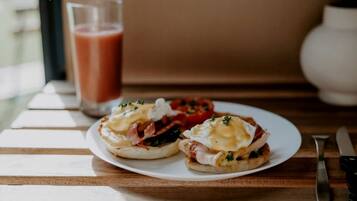 A plate with two eggs benedict sandwiches on a wooden table.
