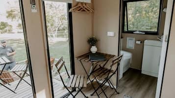 A compact kitchenette with a small table, chairs, a sink, and a window.
