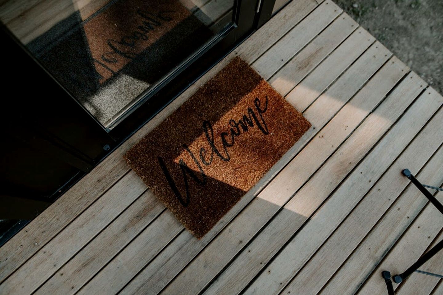 Eine Holzterrasse mit Fußmatte.