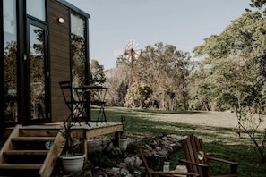 A modern building with a glass door, outdoor seating, and a windmill in the background.