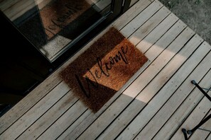 A wooden deck with a welcome mat.