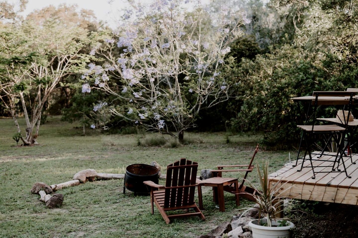 Ein Sitzbereich im Freien mit einer Holzterrasse, einem Metalltisch und zwei Holzstühlen.