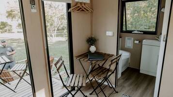 A compact kitchenette with a small table, chairs, a sink, and a window.