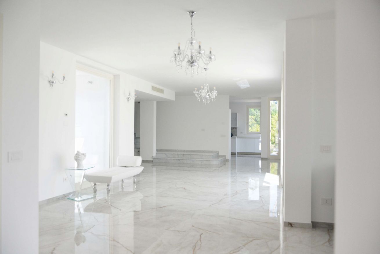 Un intérieur spacieux et bien éclairé, avec un sol en marbre, un lustre et une table en verre transparent.