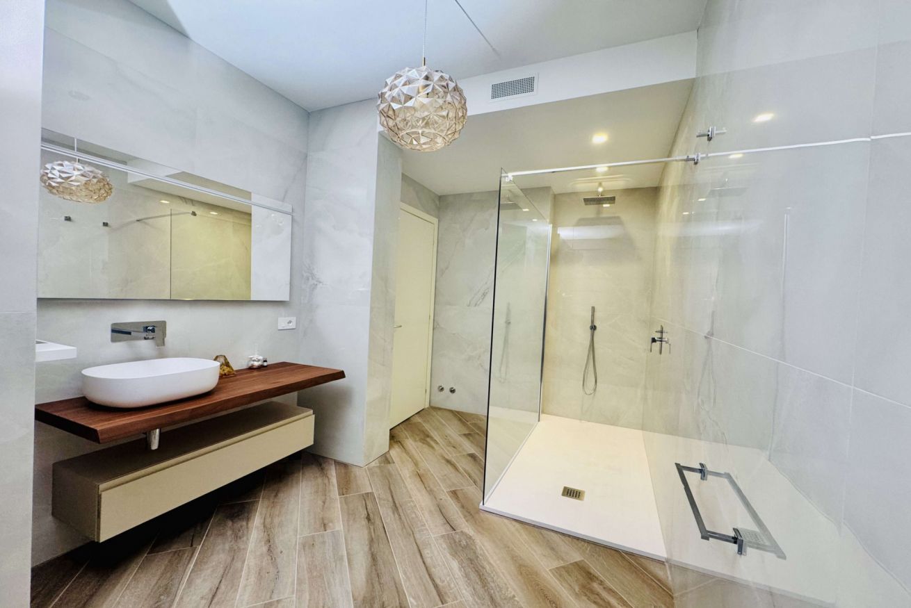 Une salle de bain moderne avec une douche à parois de verre, un meuble-lavabo en bois et un grand miroir.