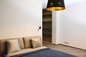 A bedroom with a bed, a bedside table, a lamp, and a closet. - Villa Eben by MMega (Conca degli Ulivi)