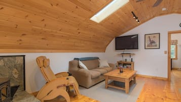 Une pièce chaleureuse avec un plafond en bois, un canapé, un fauteuil inclinable, une table basse et un téléviseur à écran plat.