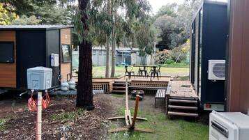 A mobile home with a deck, outdoor seating, and a small garden area.