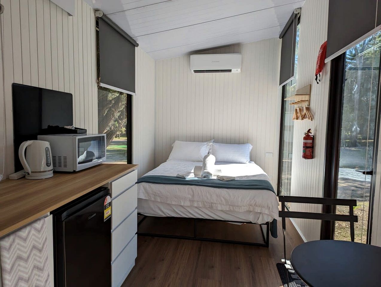 Una camera compatta con un letto, un angolo cottura, un forno a microonde, un bollitore e una finestra vista.