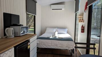 Una camera compatta con un letto, un angolo cottura, un forno a microonde, un bollitore e una finestra vista.