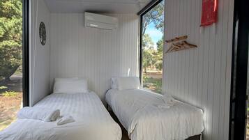 A room with two beds, a window, a fire blanket, and a wall-mounted air conditioner.