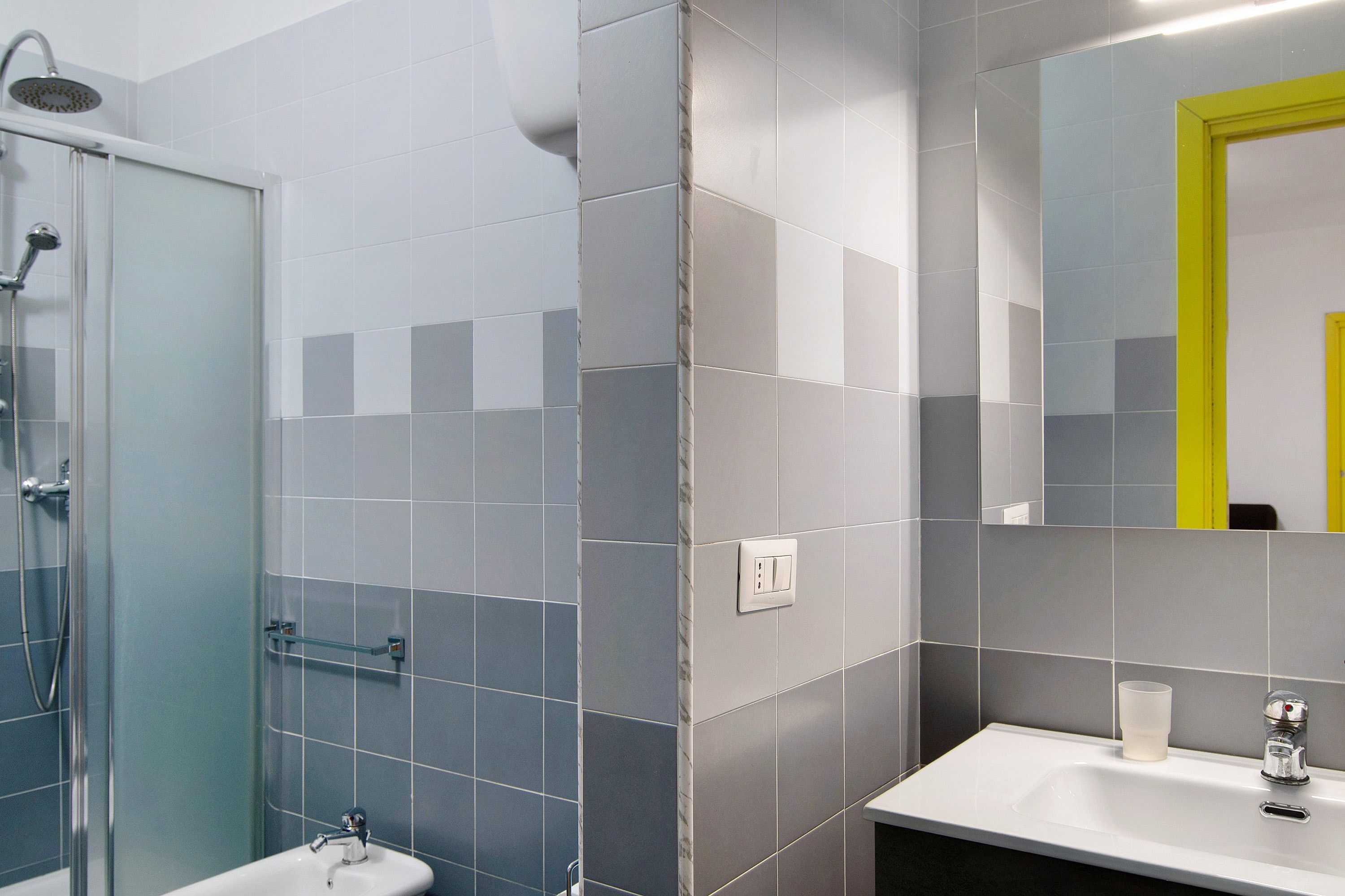A modern bathroom with a shower, sink, and mirror.