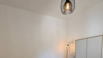 A bedroom with a bed, a bedside table, a lamp, a mirror, and a wardrobe.