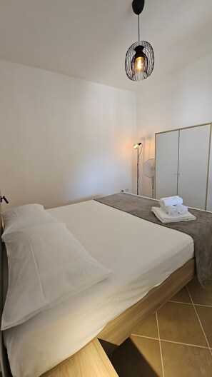 A bedroom with a bed, a bedside table, a lamp, a mirror, and a wardrobe. - Apartment 'La Radice' with Mountain View, Wi-Fi and Air Conditioning (Agropoli)
