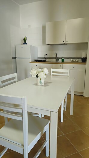 A modern kitchen with white cabinetry, a dining table with chairs, and a potted plant on the counter. - Apartment 'La Radice' with Mountain View, Wi-Fi and Air Conditioning (Agropoli)