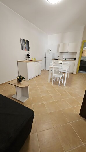 A modern kitchen with white cabinets, a dining area with white chairs, and a small table with a plant. - Apartment 'La Radice' with Mountain View, Wi-Fi and Air Conditioning (Agropoli)
