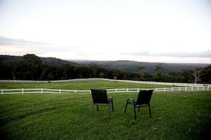 A grassy field with white fences and two chairs facing a forested landscape. - Rustic Tiny House Stay with Horse Encounters near Brisbane Water National Park, Calga NSW (Glenworth Valley)