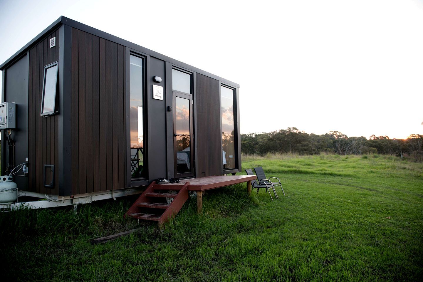 A modern, single-story cabin with a flat roof, large windows, and a wooden deck.