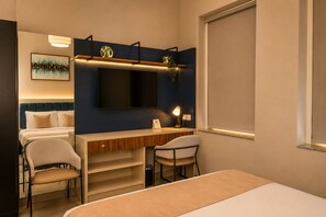 Une chambre d’hôtel avec un lit, un bureau, deux chaises, une télévision et un tableau au mur.