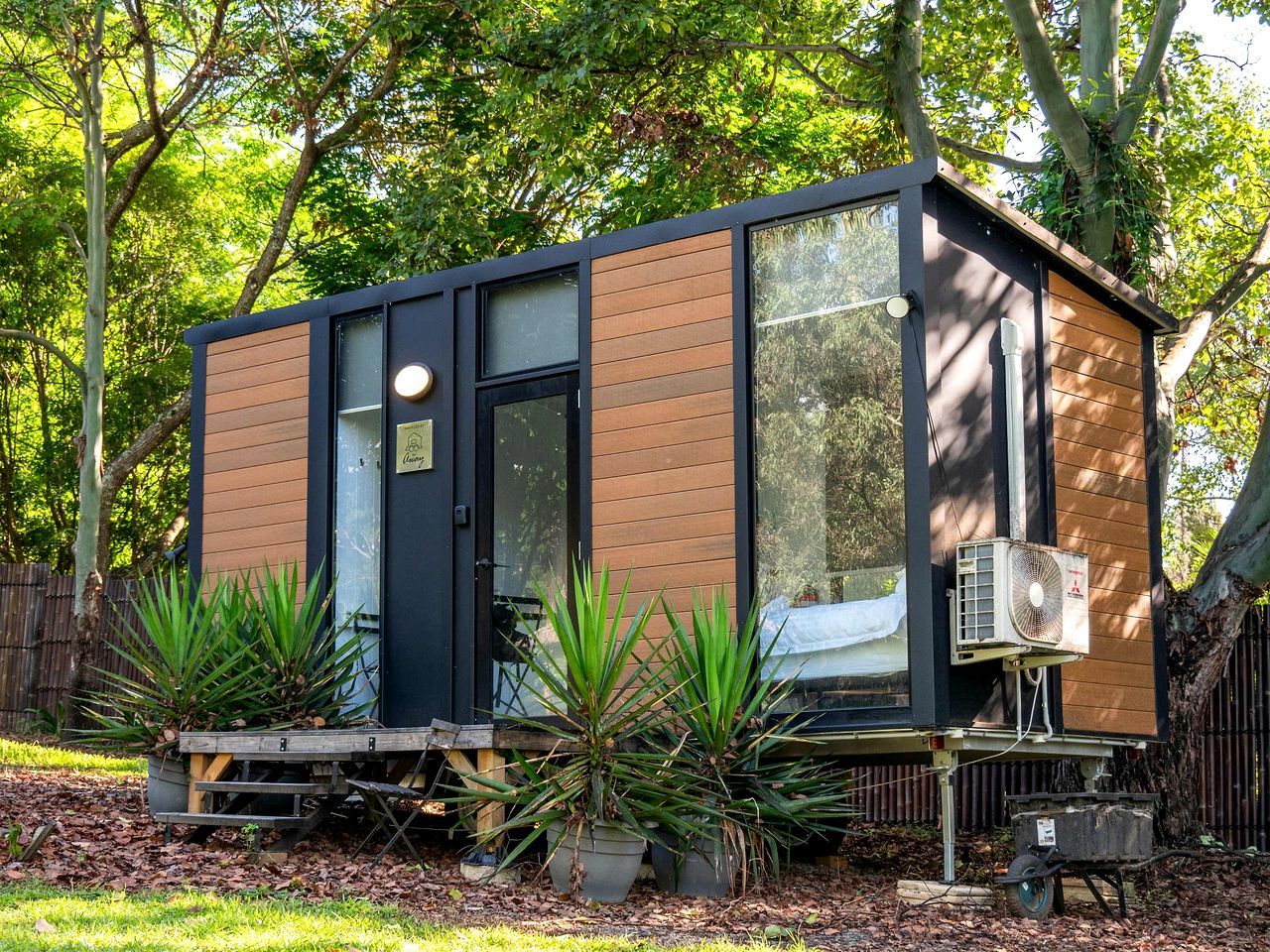 A modern, compact cabin with a large window, a door, and an air conditioning unit.