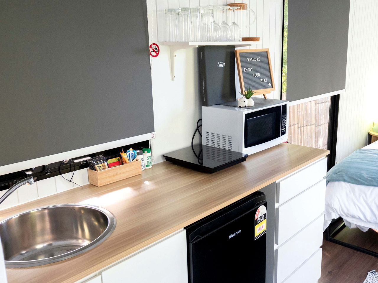 A compact kitchenette with a sink, microwave, and a small refrigerator.