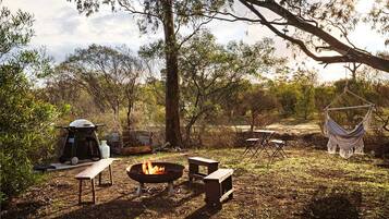 Ein Campingplatz mit Feuerstelle, Picknicktischen, einer Hängematte und einem Zelt.
