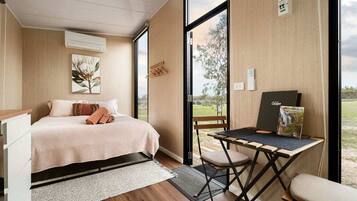 Un dormitorio con cama, escritorio y vistas al exterior.