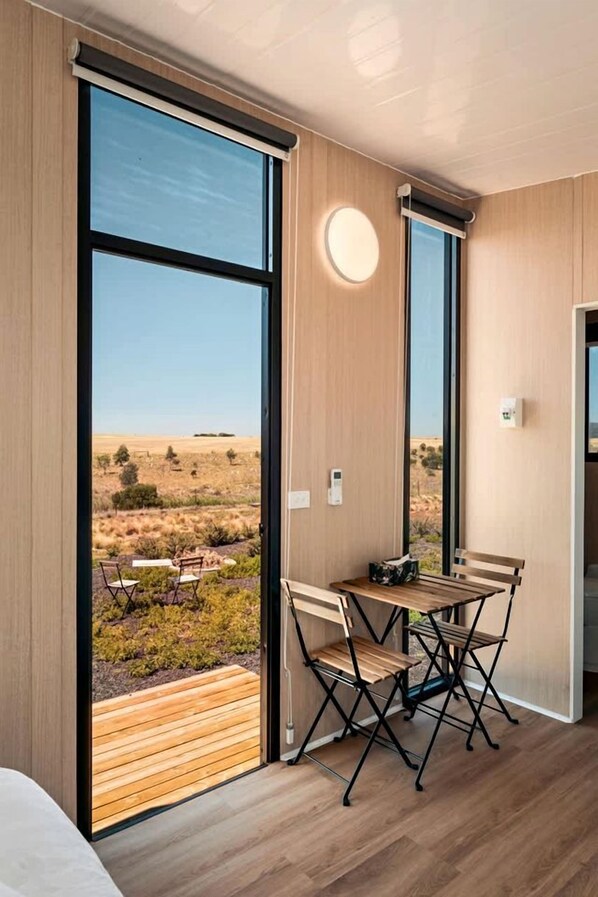 A room with large windows, a wooden table, and chairs.