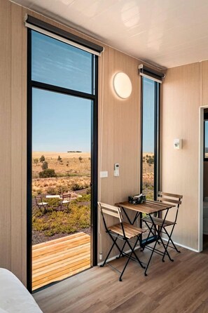 A room with large windows, a wooden table, and chairs.