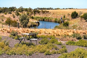 A natural landscape with a small pond, grassy areas, and a picnic table. - Remote Equipped Tiny House Majestic Sunset Views in Victoria (Wyndham Vale)