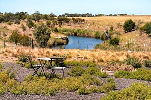 A natural landscape with a small pond, grassy areas, and a picnic table.