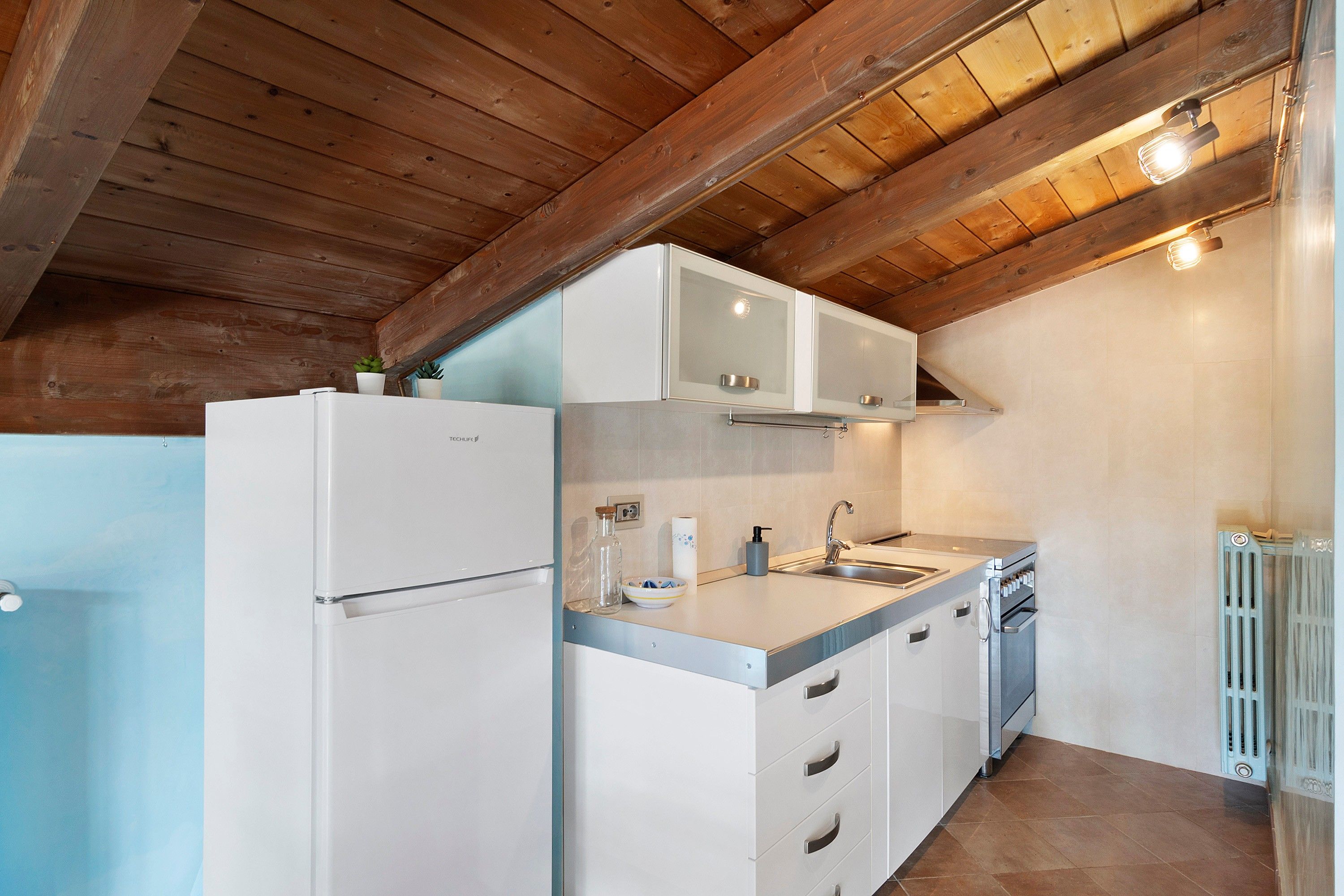 A compact kitchen with white cabinetry, a built-in oven, and a sink.