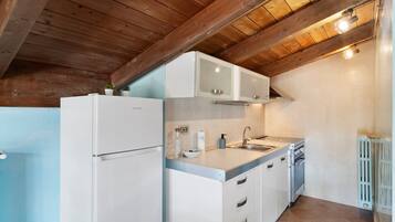 A compact kitchen with white cabinetry, a built-in oven, and a sink.