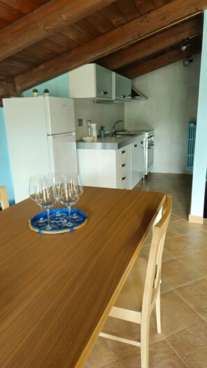 A dining table with a blue tray and wine glasses, a kitchen area with white cabinets, and a tiled floor. - Apartment 'Suite Unikum' with Mountain View, Wi-Fi and Air Conditioning (Agropoli)