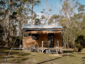 A wooden cabin with a metal roof, surrounded by trees.