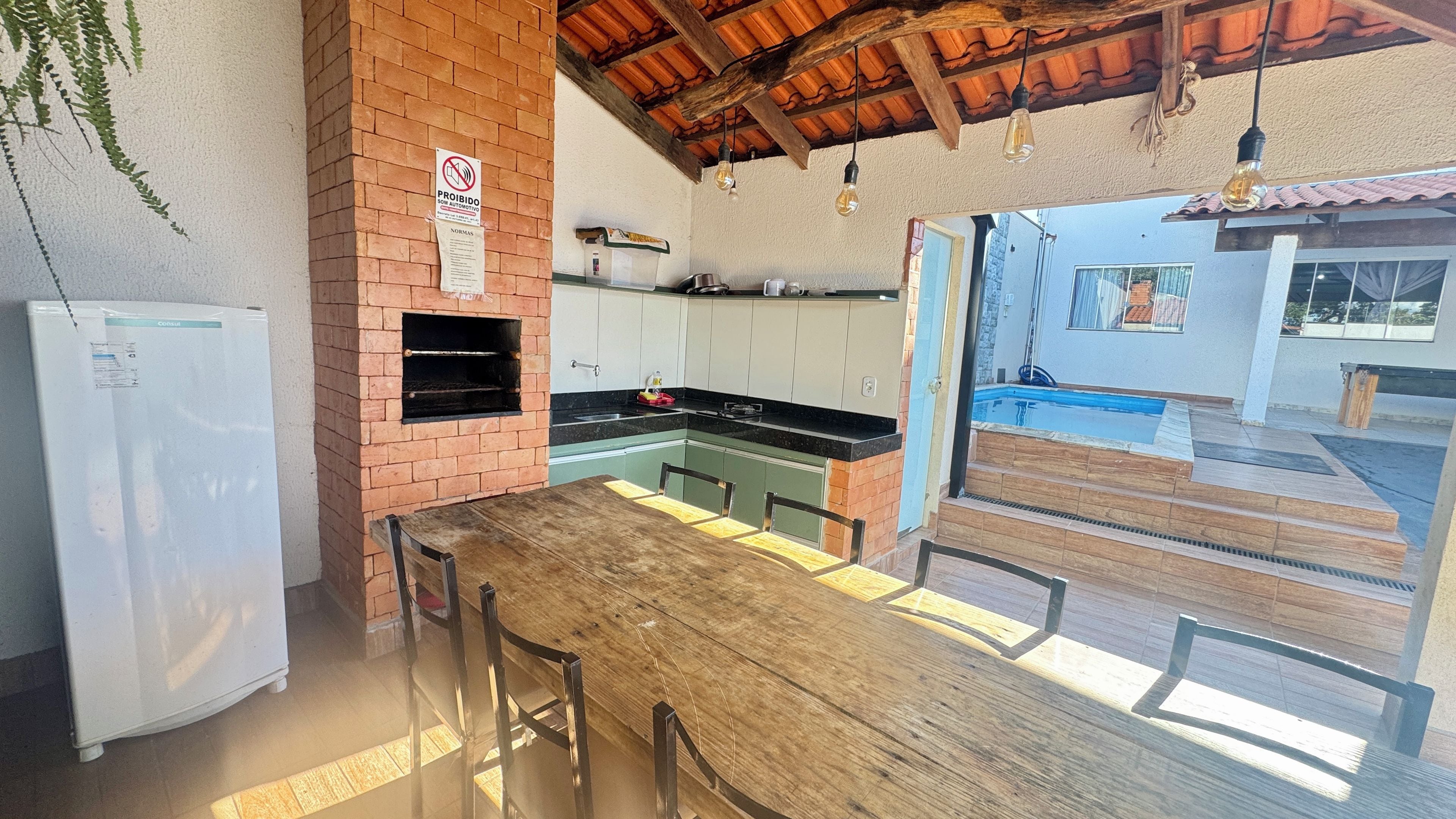 A kitchen with a brick oven, a refrigerator, and a dining area with a wooden table and chairs.