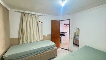 A room with two beds, a wooden door, a mirror, and a light fixture.