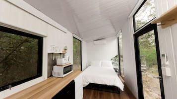 A compact bedroom with a bed, bedside table, and a window.